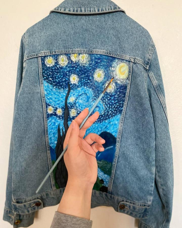 Denim jacket with painted swirling blue and yellow starry night design from @leylibedik showing creative wearable artwork.
