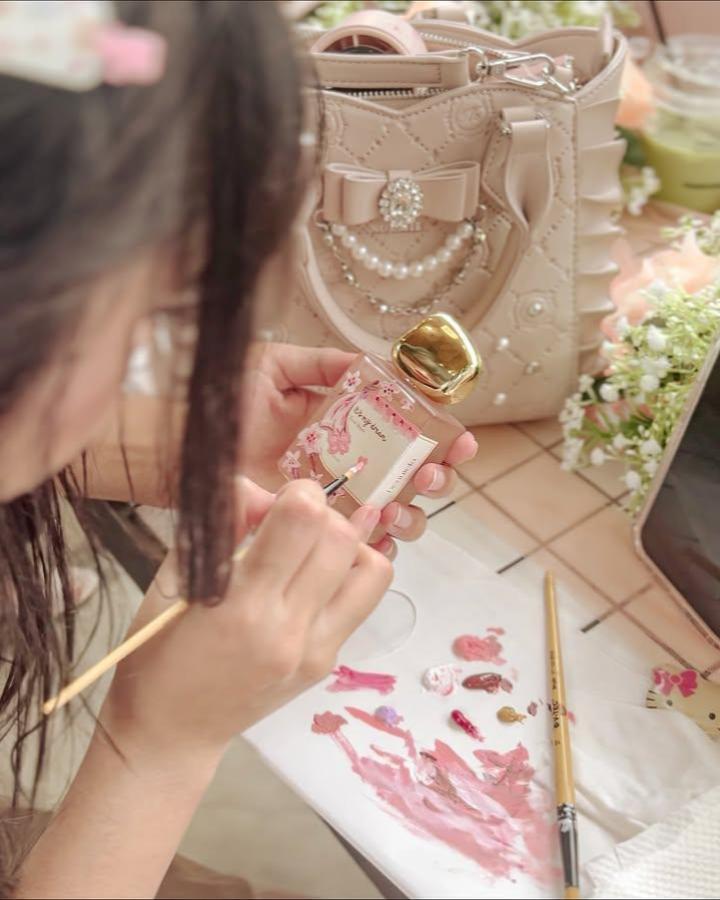 Soft pink floral hand-painted small bottle with gold cap from @studio_nana.id. Detailed miniature art with multiple colors on everyday object.