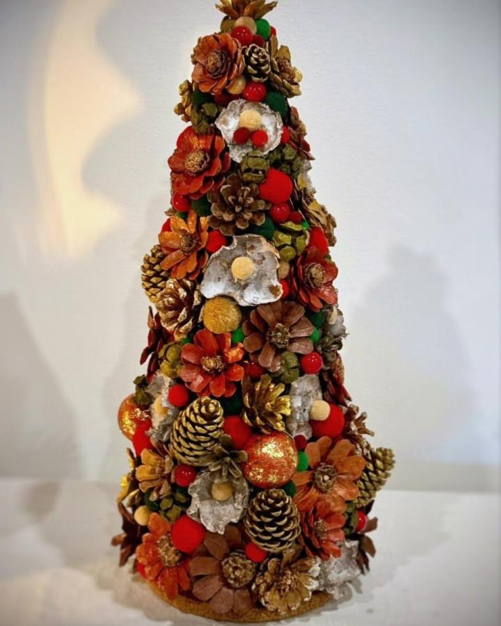 Orange and gold accented pine cone craft tree from @claudia.carlsen featuring natural textures and festive color pops.