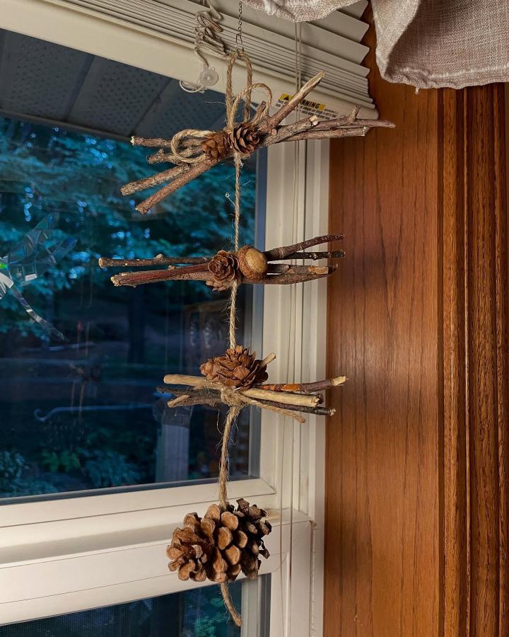 Natural twig and pinecone hanging mobile craft by @painted_creations_by_donna with rustic jute twine and dried seed pod accents. Simple, earthy decor.