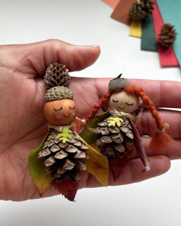 Natural pine cone fairy dolls with autumn leaves and acorn caps by @creative_mama_che. Handcrafted woodland-themed miniature figures.