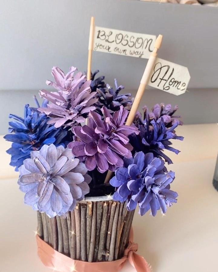 Purple and blue hand-painted pine cones in twig vase with ribbon from @artischic_anvesha. Rustic colorful centerpiece craft.