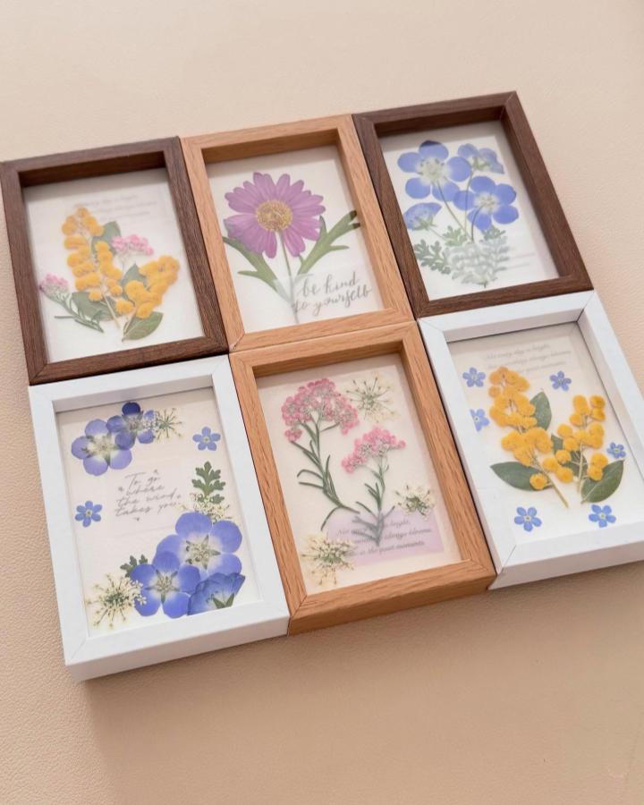 Framed pastel and yellow pressed flower collage art from @matsumatsu1223 with delicate botanical layering and handwritten text.