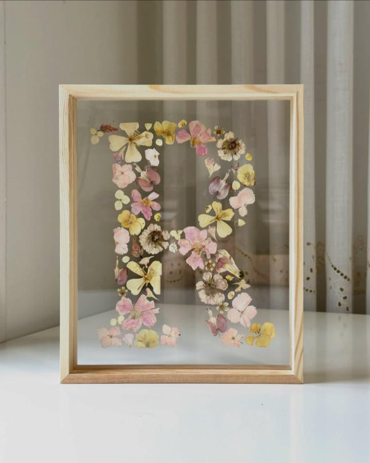 Pressed pale pink and yellow floral letter art in a light wood frame from @juliaflorastudios. Personal and natural decorative craft piece.