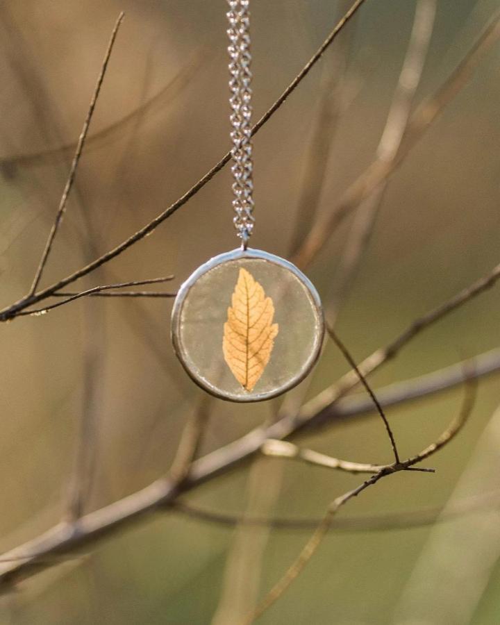 Yellow dried leaf pendant necklace hanging on silver chain from @sako.crafts. Nature-inspired wearable resin art jewelry piece.