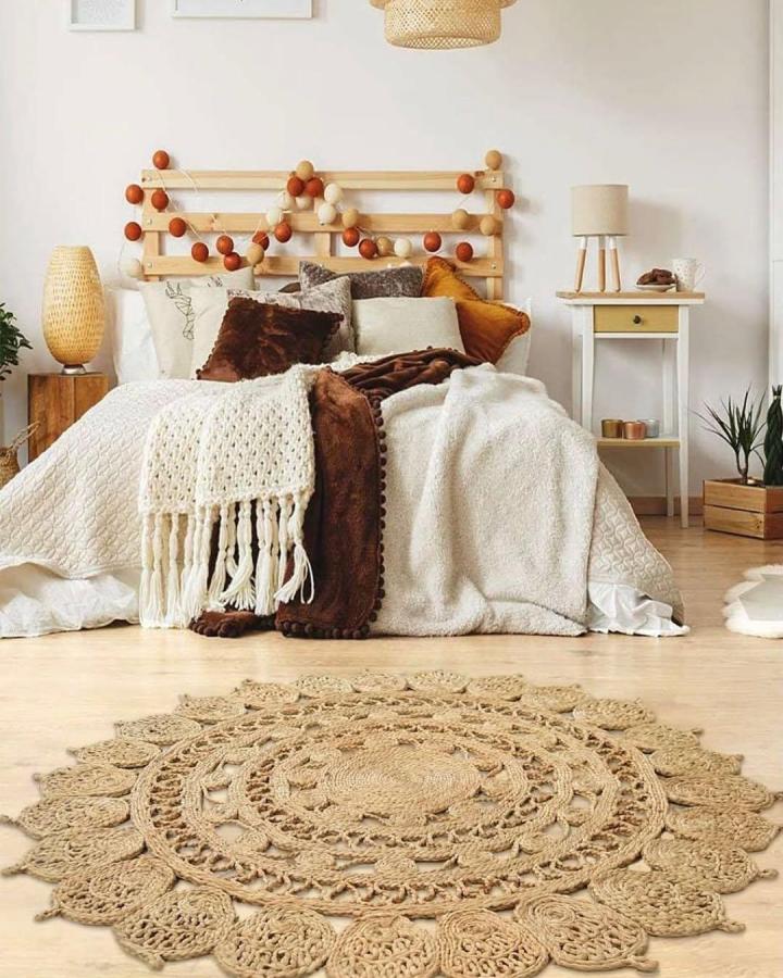 Natural tan handwoven jute rug from @sharmas.india showcases intricate knots and boho charm in a cozy bedroom setup.