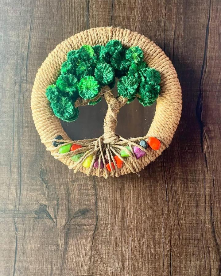 Natural jute rope framed mirror with handmade pom-pom tree and colorful stones wall art by @artisanat_1920 creating rustic charm and texture.