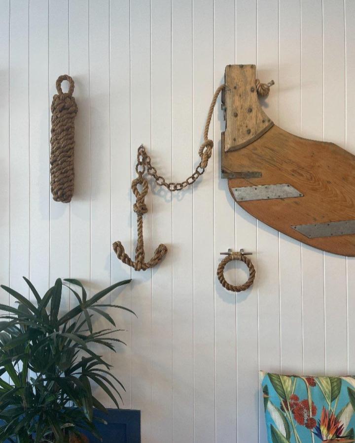 Natural fiber nautical rope anchor wall decor ideas by @jacktarslocker. Rustic coastal style with wood and metal accents on white wall.