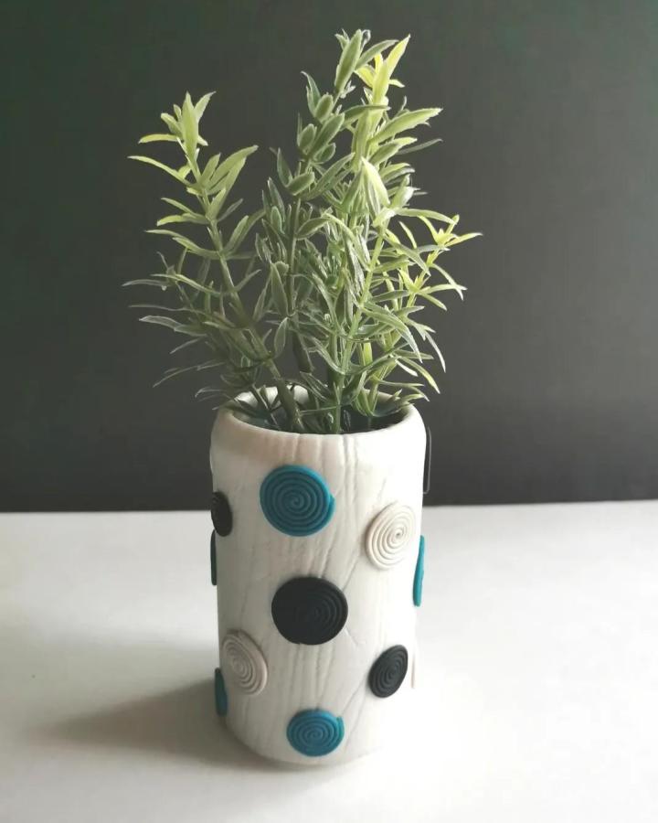 White polymer clay planter with blue and black dots tin can crafts from @mapleaccents featuring textured clay decoration and greenery inside.