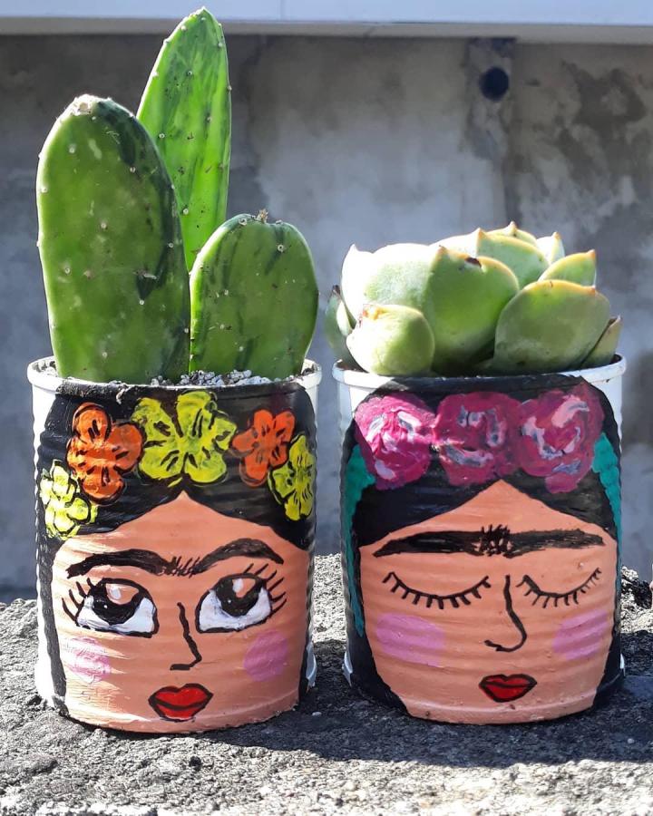 Painted folk art style tin can planters with succulents from @imkillerlooks featuring bold floral crowns and colorful face details.