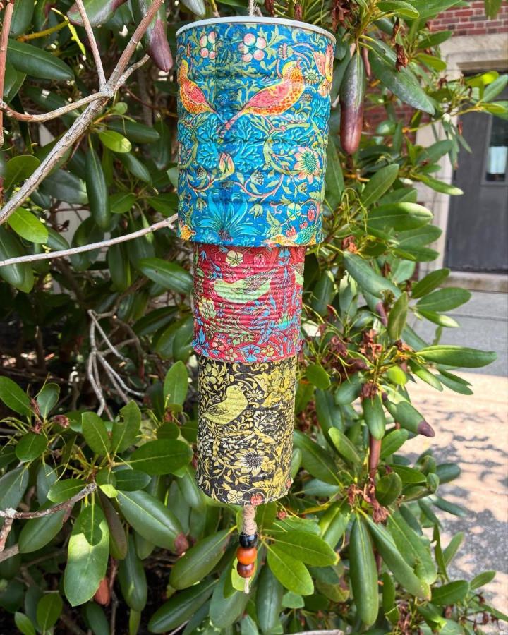Bright colorful bird-patterned recycled metal wind chime from @barringtonlibrary_teens. Three stacked decorated cans with beads and twine.