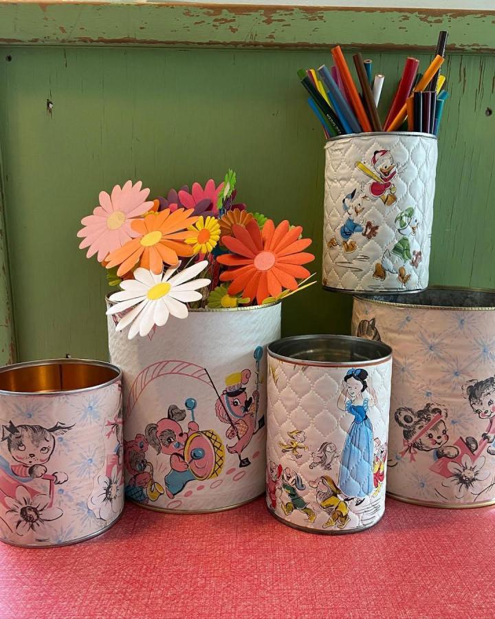 Quilted vintage vinyl tin can crafts by @magpieethel featuring pastel colors and cartoon designs holding pencils and flowers.