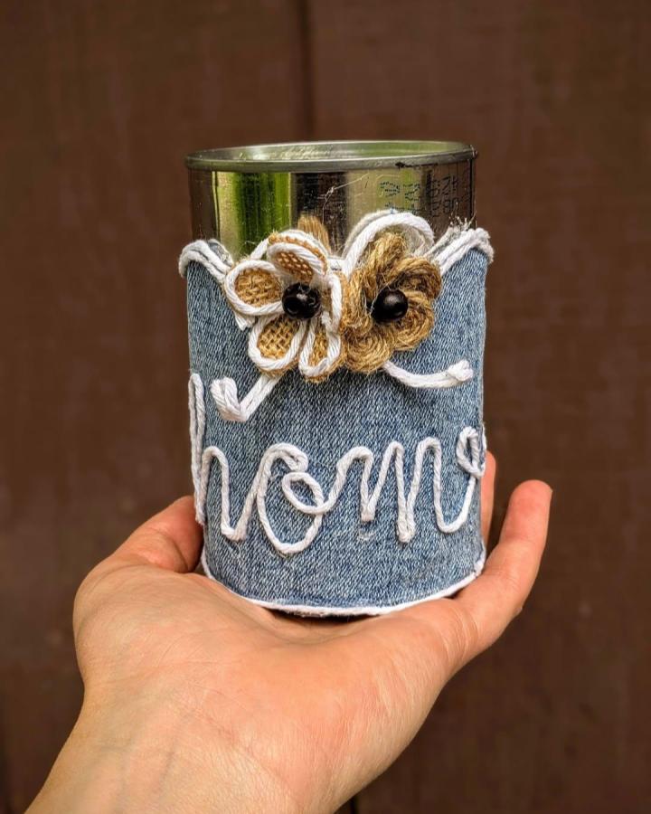 Denim wrapped tin can with white rope lettering and burlap flowers from @hearthandtwine held in hand. Rustic craft idea.