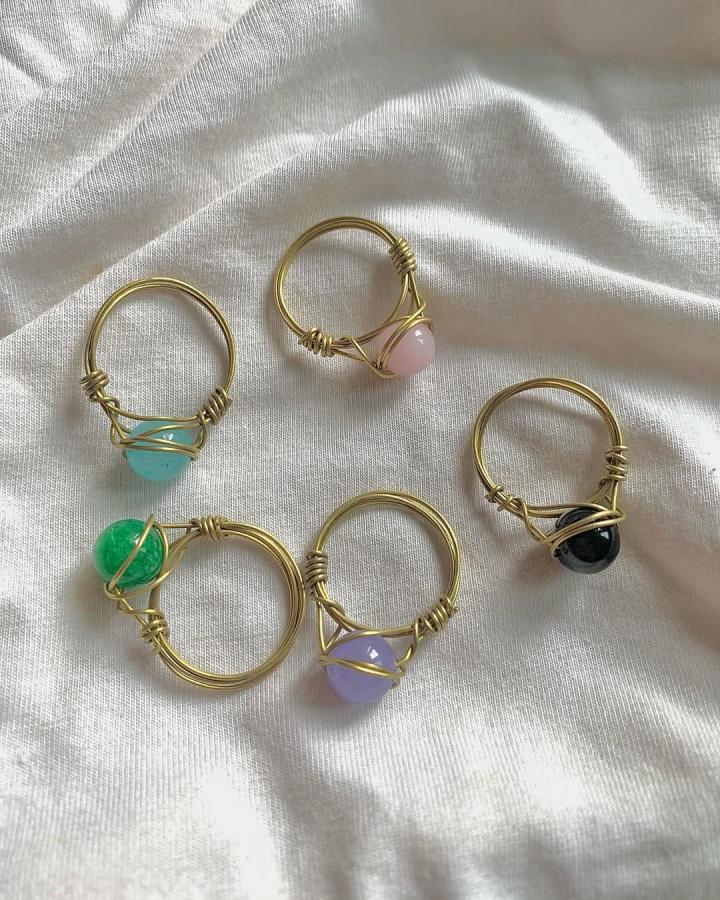 Colorful gemstone rings with gold wire wrapping on white fabric by @handmade_it_xo. Handmade and artistic jewelry style.