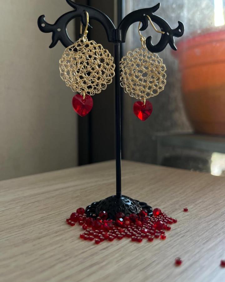 Golden wire crochet earrings with red heart beads from @mara.atelier.joyas. Delicate handmade loop design with bright contrasting crystal accents.