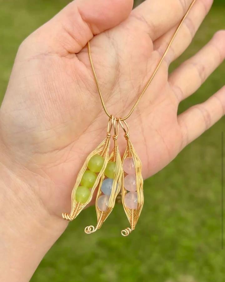 Gold wire wrapped crystal bead pod pendants by @mtedenvillagecraftmarket22. Handmade, nature-inspired jewelry with colorful stones.