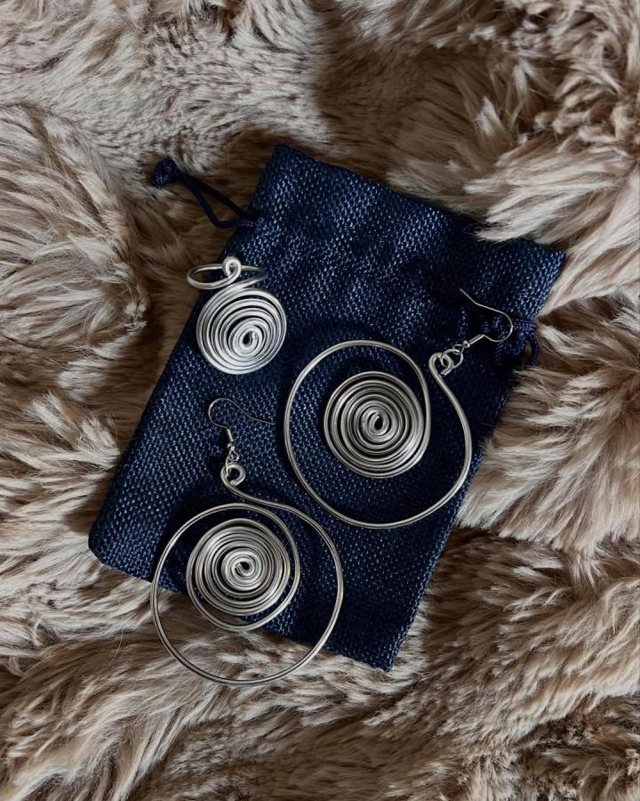 Silver spiral wire earrings and ring on navy pouch by @carlottavendramin.art showcasing unique wire jewelry ideas and bold circular designs.