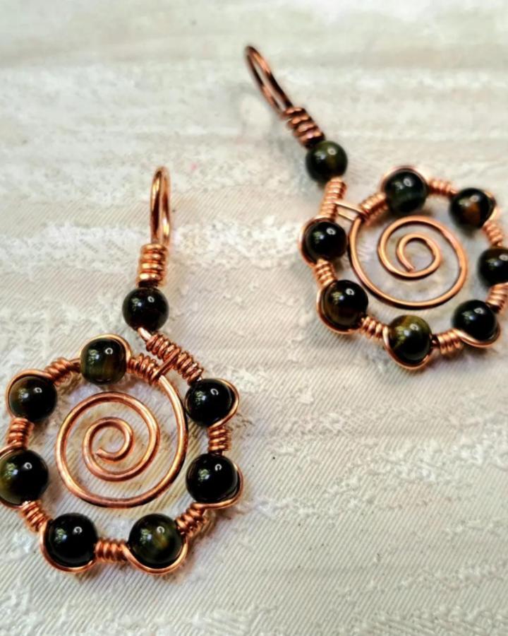 Copper wire spiral earrings with dark beads from @jemhawkesjewellery. Handmade wire wrapped ammonite inspired pendant design.