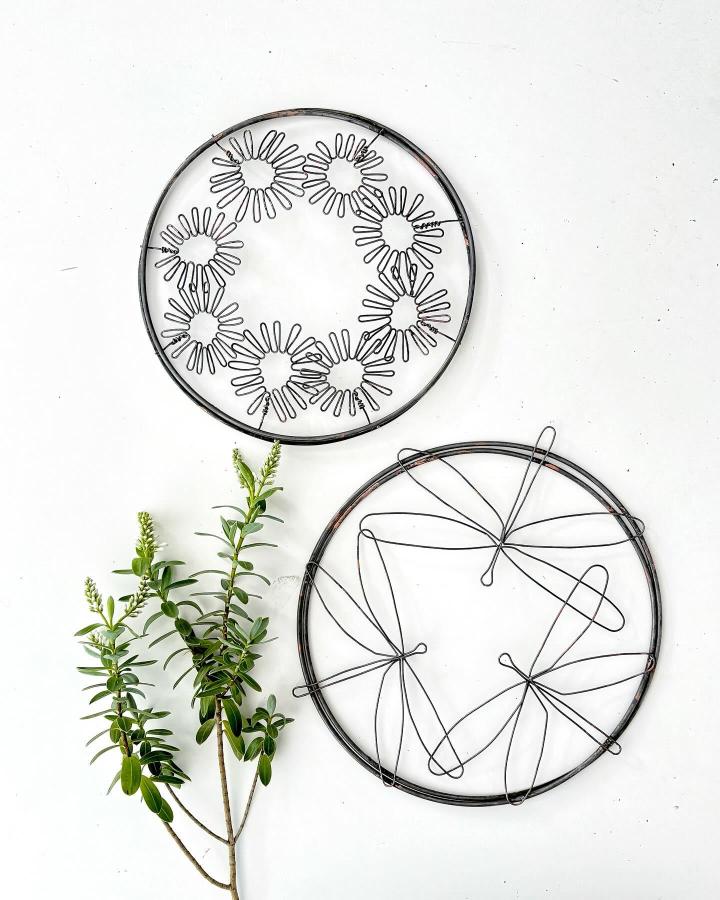 Black wire floral wall sculptures by @ruby_and_jack_design. Minimalist circular designs creating delicate, handcrafted botanical shapes.