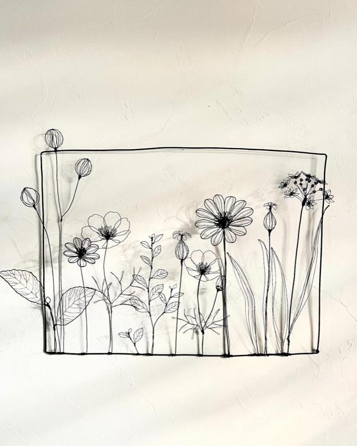 Black wire floral wall art by @ss.art___wirecraft. Intricate garden-inspired linework inside a simple frame.