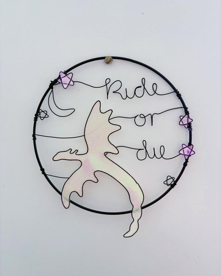 Black wire circular wall art from @thewirenook featuring whimsical silhouette and pastel star accents with expressive lettering design.