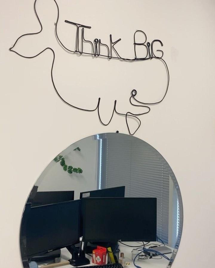 Black wire bird and phrase wall art above a round mirror from @wirearty. Minimalist and inspirational home decor piece.
