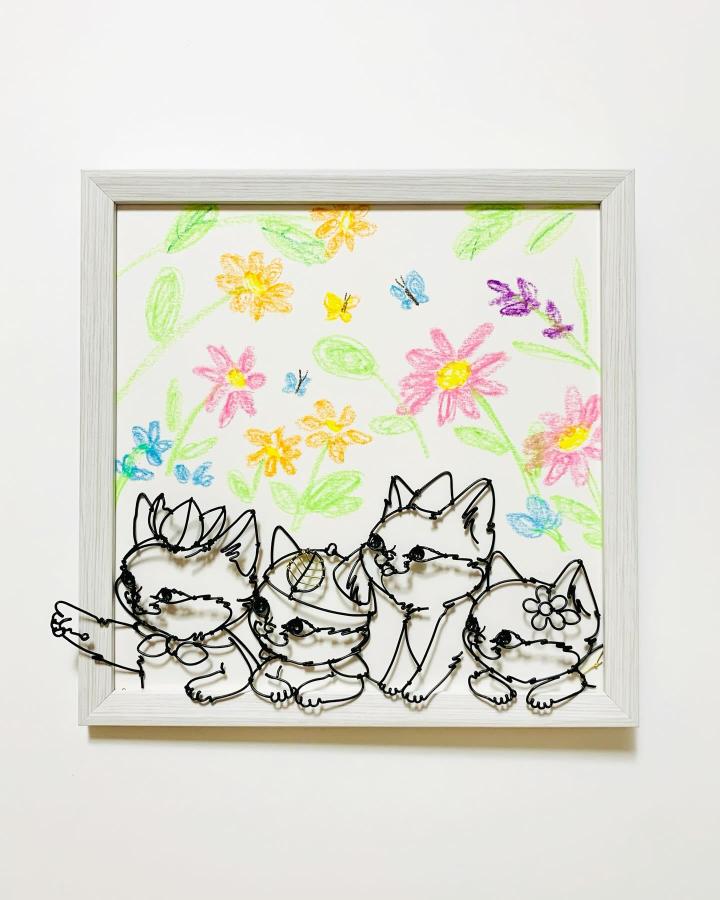 Black wire cats perched on a bright floral background by @saaya_wireart. Playful and charming home decoration with hand-drawn flower accents.