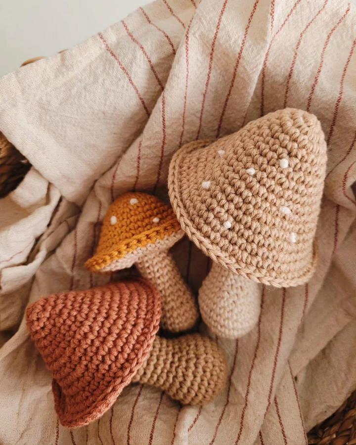 Beige and rust crochet mushrooms with white spots from @floreocrochetdesign. Soft textured handmade forest-inspired decor pieces.