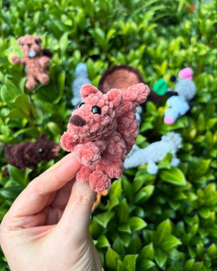 Plush dusty rose and brown finger puppet from @itsnotadishcloth showcasing woodland crochet pattern ideas in a natural garden setting.