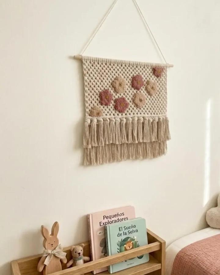 Neutral macramé wall hanging with floral motifs and fringe from @miminapena. Cozy earthy tones and textured yarn design.