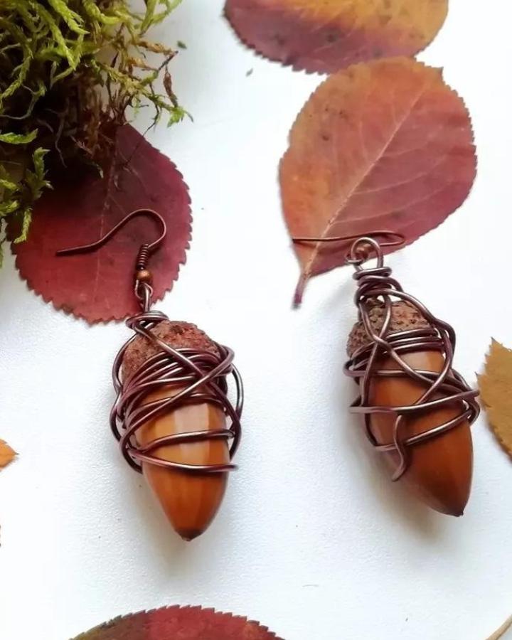 Polished acorn earrings wrapped with copper wire from @lovelynatureforyou natural rustic jewelry design.