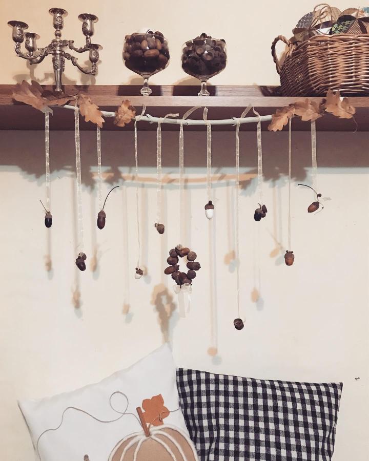 Natural brown and white acorns hanging on cream ribbons from a branch by @ildiko._.sz Rustic fall decor display.