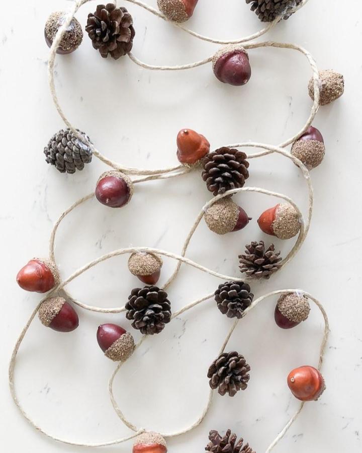 Natural acorn and pinecone garland with twine by @thehappyhousie showcasing a rustic autumn decoration idea.