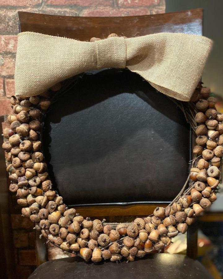 Natural brown acorn and burlap wreath from @debleefas. Rustic handmade fall decor on dark chair.