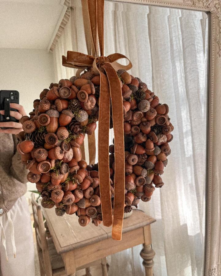 Natural brown acorn wreath with velvet ribbon from @idyll.in.everyday.life showcasing creative acorn crafts for adults in cozy home decor.