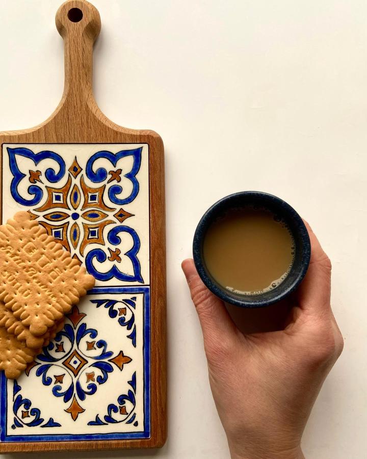 Blue and caramel floral ceramic tile serving board with biscuits and coffee cup from @yelimozdinc_artwork showing detailed hand-painted tile designs.