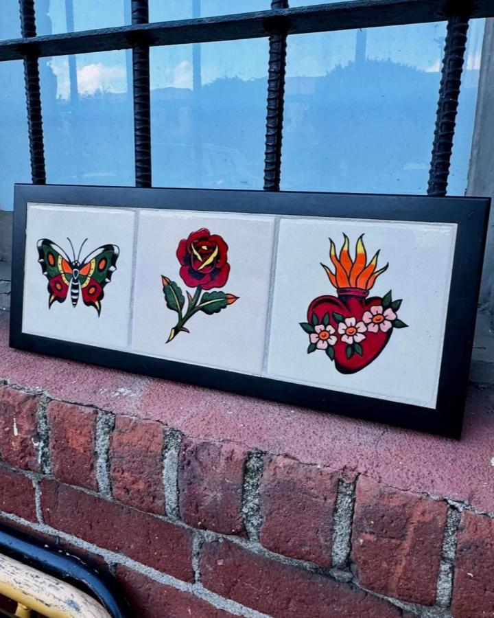 Bright colorful tattoo-inspired ceramic tile set from @cheweymolina with butterfly rose and flaming heart designs on white tiles.