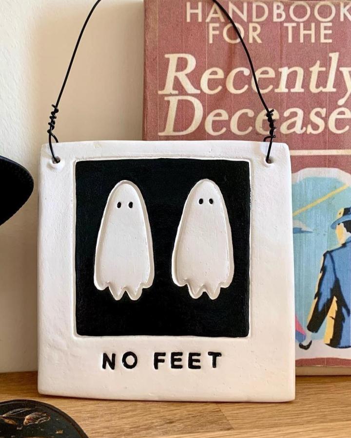 White and black ceramic tile wall hanging from @blyartworks featuring cute ghost design with playful text.
