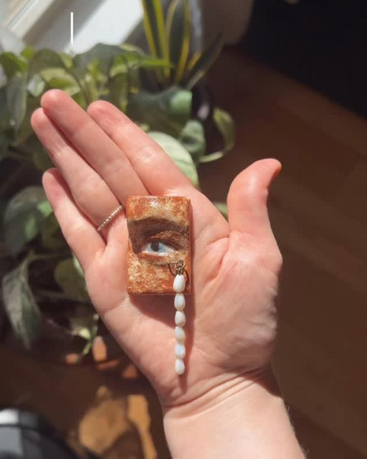 Handmade rustic ceramic tile with painted eye and white beaded tassel by @camilla.crittenden. Miniature artistic craft piece.