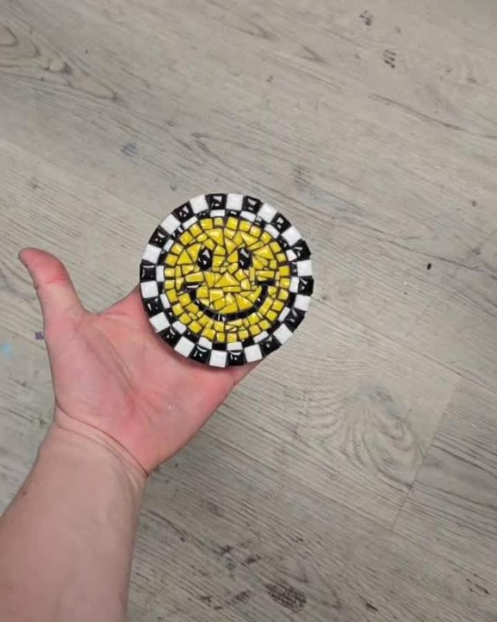 Yellow smiley face mosaic coaster with black and white border made from small ceramic tiles by @williamgeffkenart. Bright and playful tile artwork.