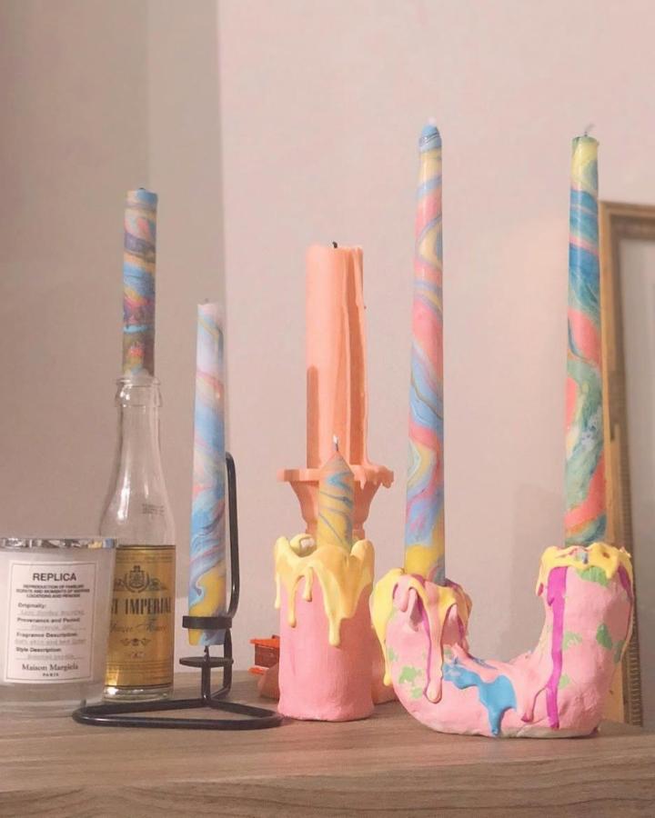 Pink clay candle holders with yellow wax drip detail and pastel swirl candles by @pitapat.vintage. Unique handmade sculptural candle decor.