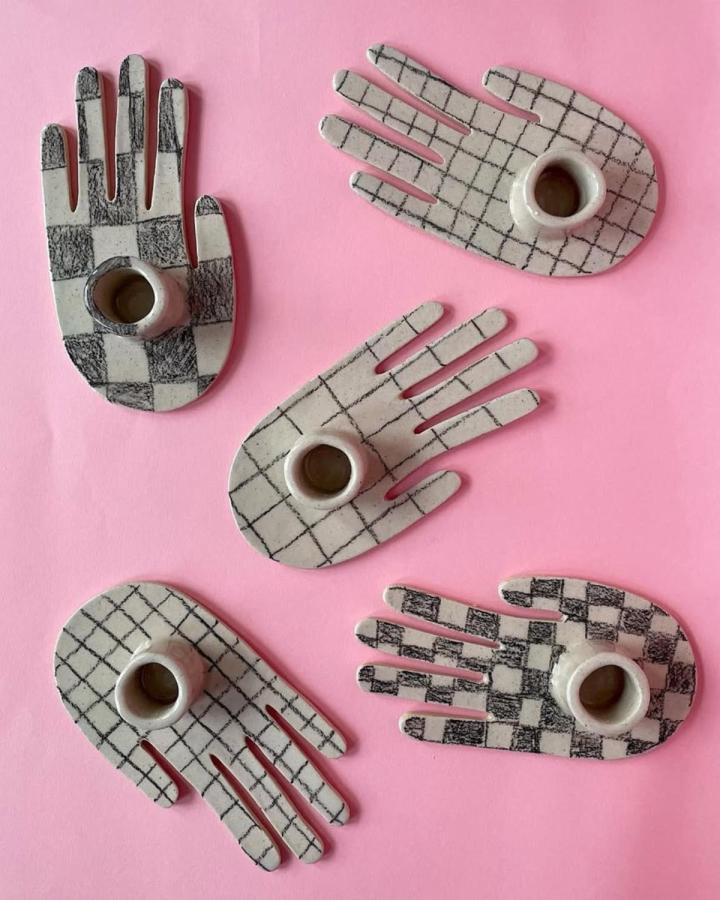 Black and white checkered hand-shaped clay candle holders on pink background by @score.and.fold. Unique and playful craft design.