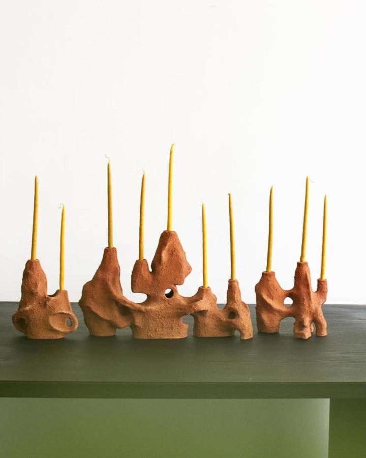 Terracotta abstract sculptural candle holders with mustard yellow tapers from @unfold.projects inspired clay candle holder craft ideas in warm earthy tones.