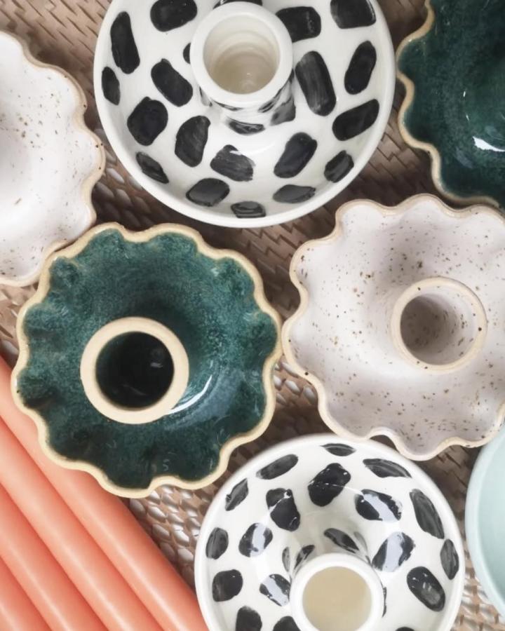 Green and cream ceramic candle holders with wavy edges and spotted patterns by @lyazdabadi. Glossy finish on handmade pottery.