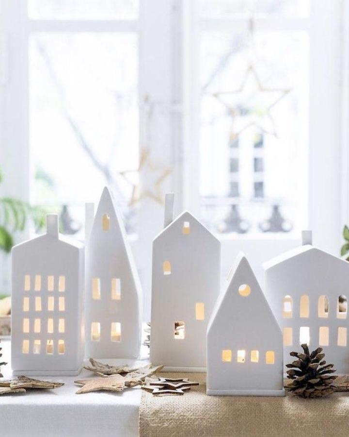 White minimalist ceramic house candleholders by @hobiigunluk. Simple clean design with warm window cut-outs creating cozy light effects.