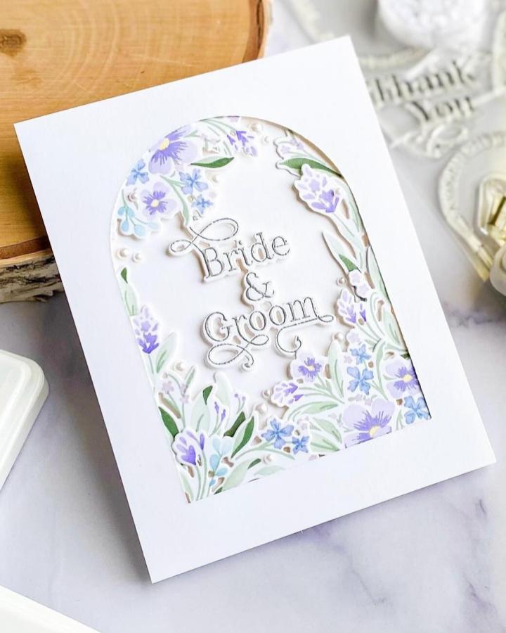 Pastel floral frame with white cutout card from @humorbean_cards. Soft, elegant diy wedding card ideas featuring layered flowers and script text.