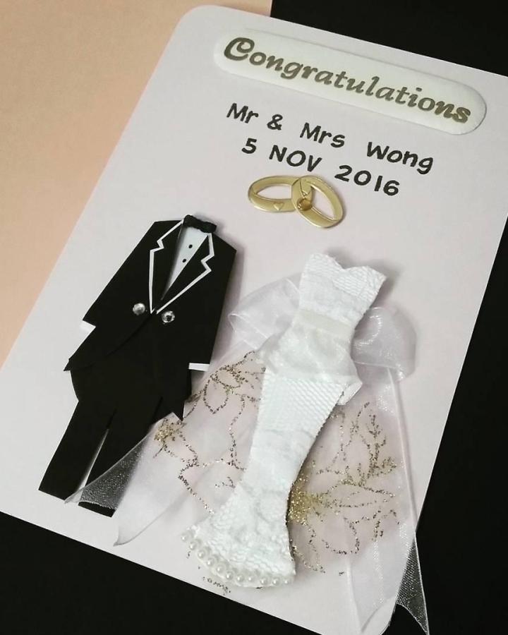 White lace and black paper miniature wedding dress and tuxedo card from @gloglolandhandcraft. Handmade textured wedding invitation with ribbon and pearl accents.