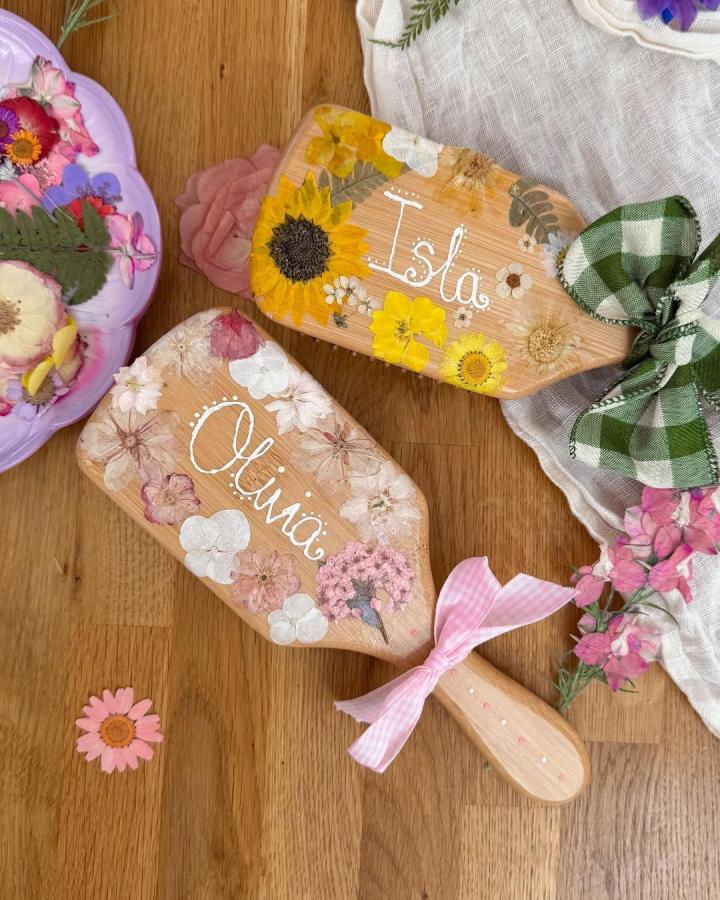 Pressed floral decorated wooden paddles with personalized names and ribbons from @mummywifeandlisaslife showcasing creative natural decor crafts.