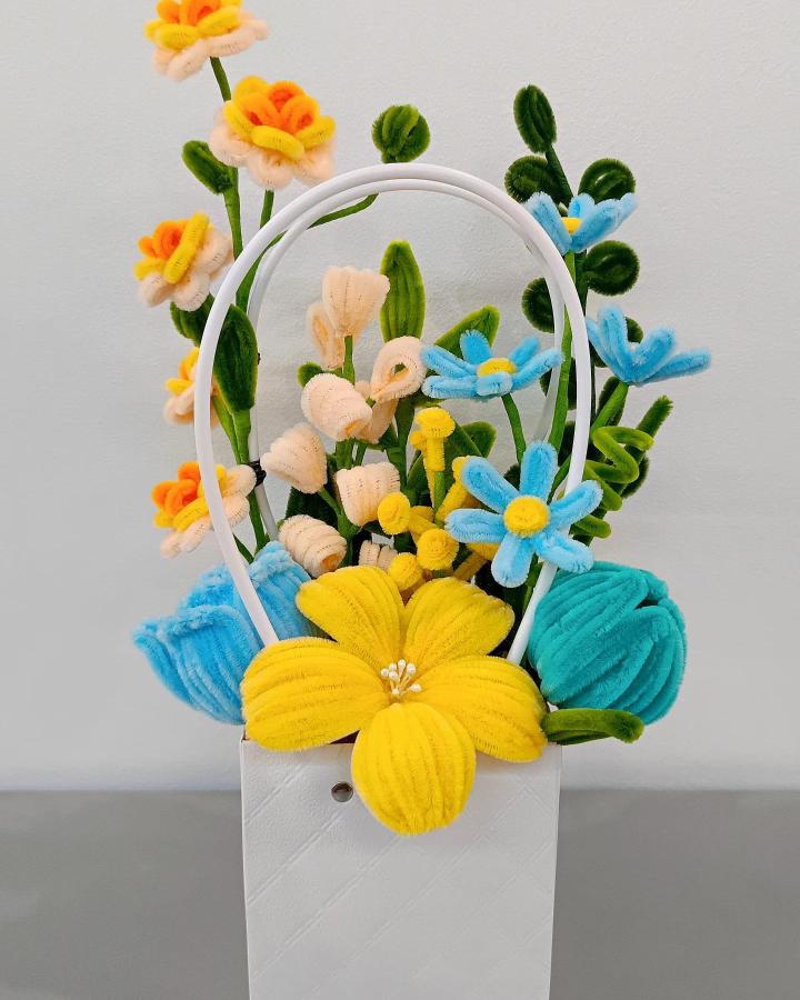 Bright colorful fuzzy wire flower arrangement from @emmyctln with playful soft texture and varied shapes in a white container.