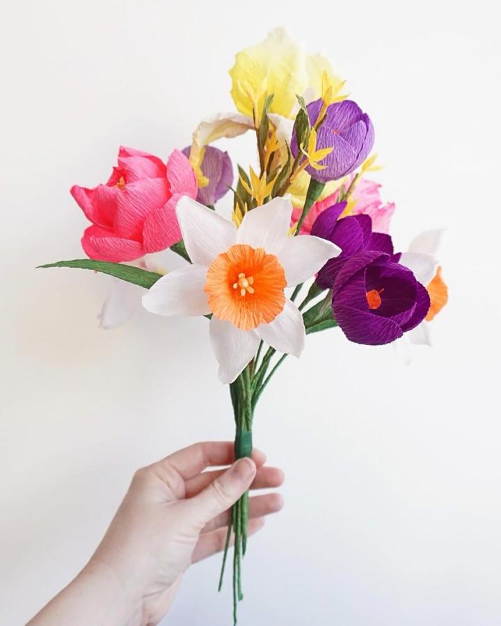 Bright colorful crepe paper bouquet held by hand showing detailed handcrafted flowers by @besspapergoods. Simple elegant paper floral art.
